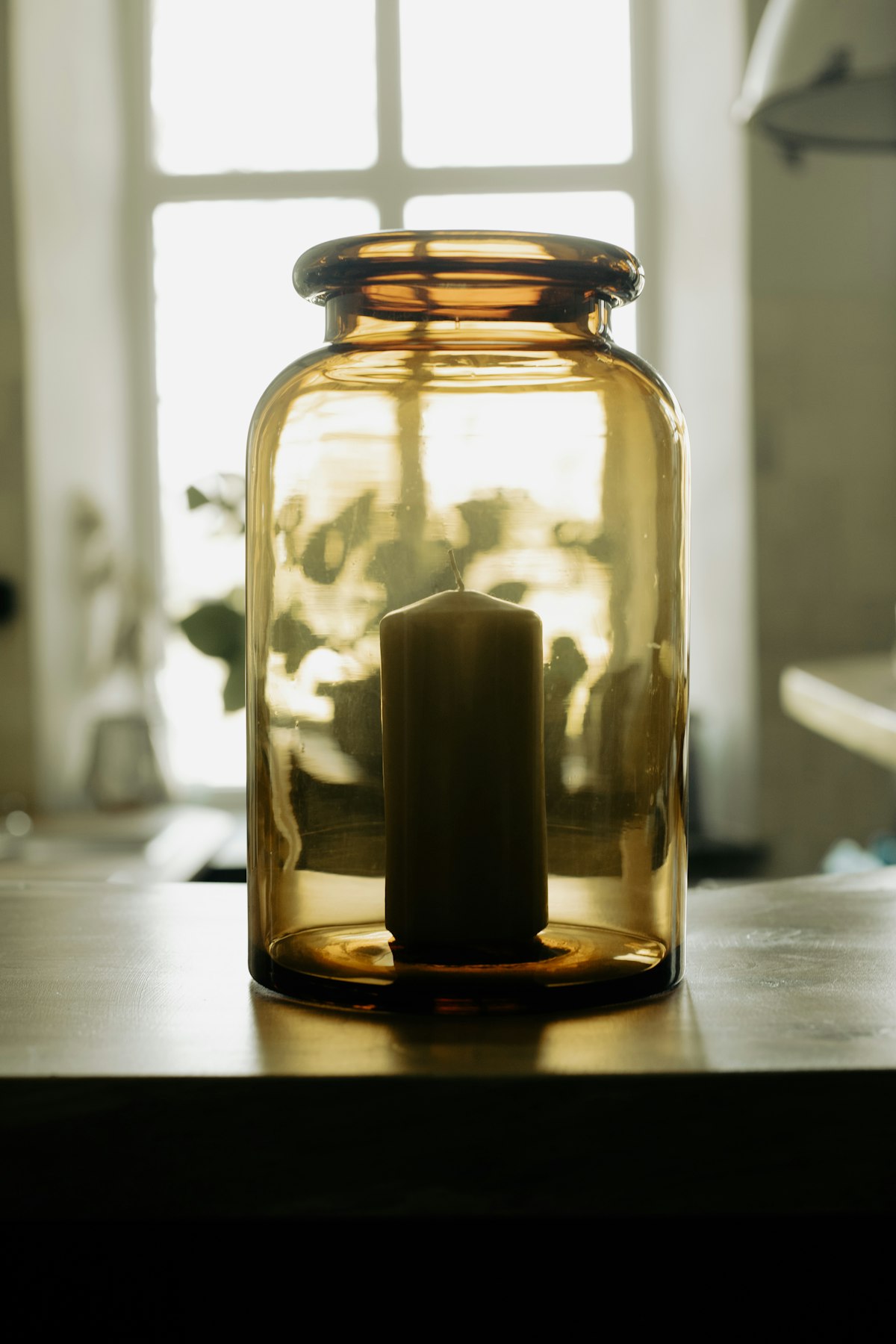 A glass hurricane lantern with a brass base